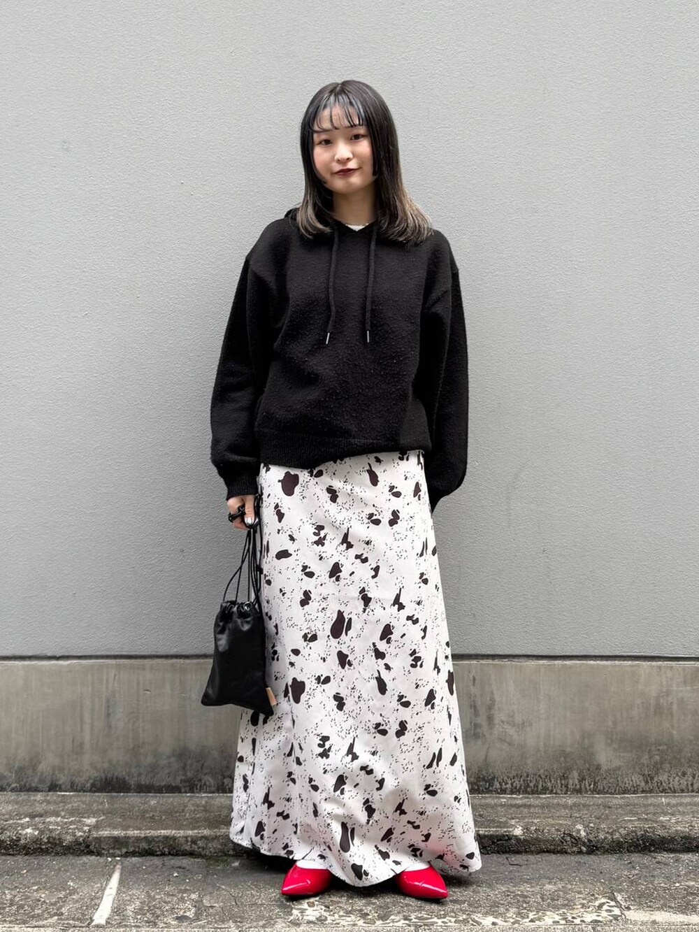 ブラック系のショルダーバッグ、レッド系のパンプス、ブラウン系のスカートを着用したレディースの春コーディネートの3枚目の写真