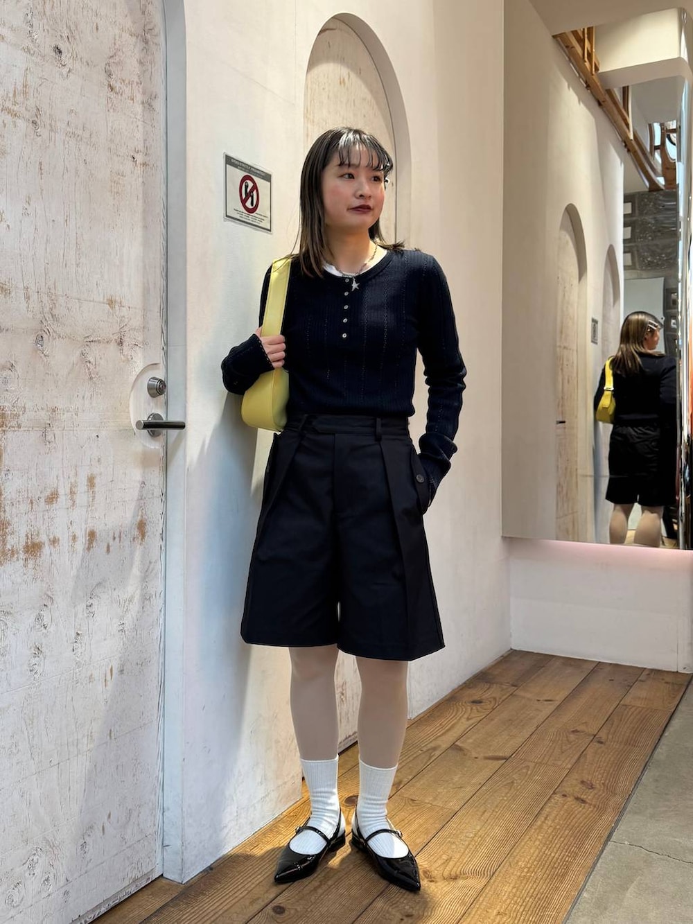 ブラック系のパンプス、ブラック系のスラックス、イエロー系のショルダーバッグを着用したレディースの春コーディネートの3枚目の写真