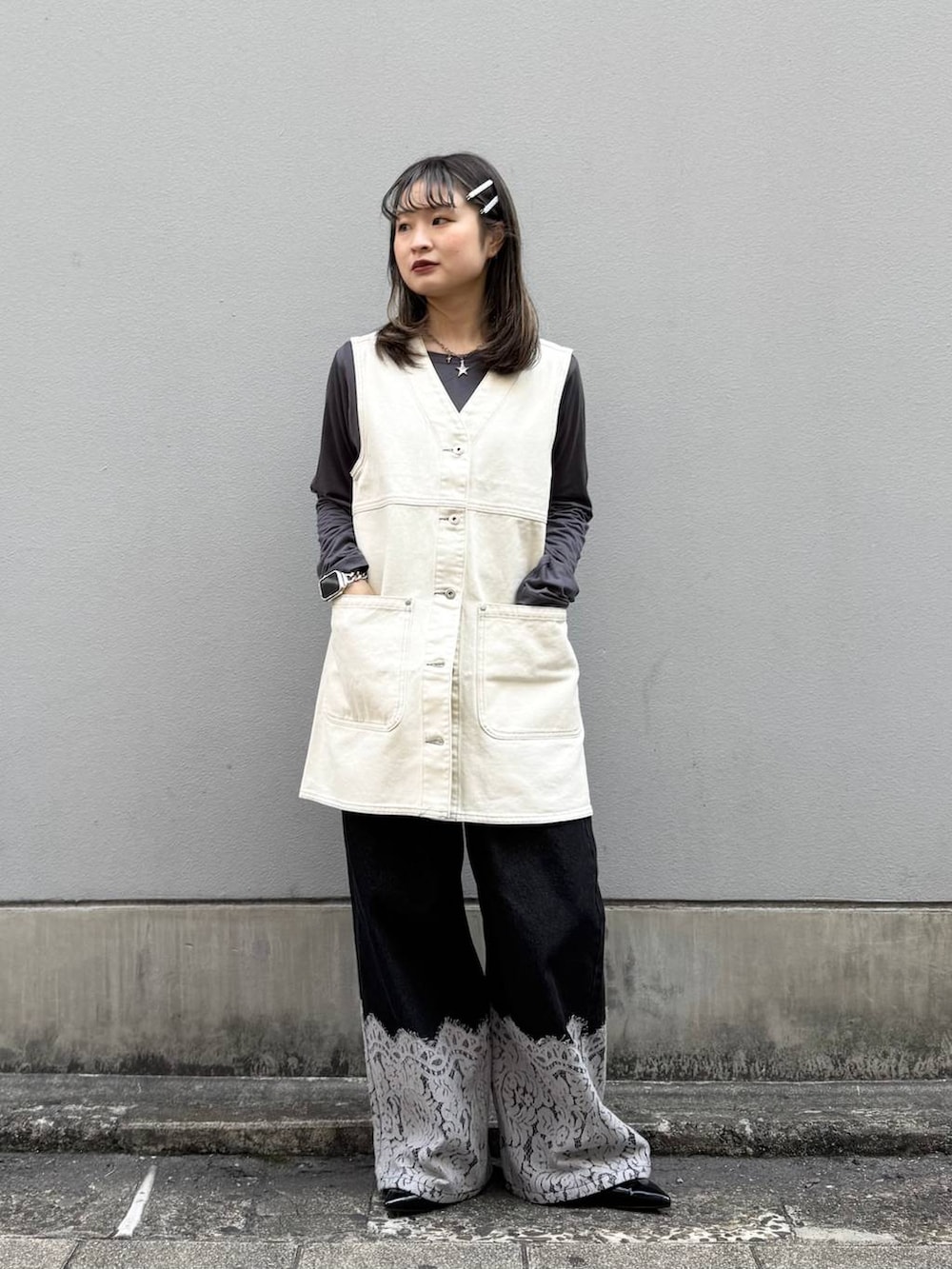 ブラック系のパンプス、ホワイト系のワンピース、ブラック系のデニムパンツを着用したレディースの春コーディネートの2枚目の写真