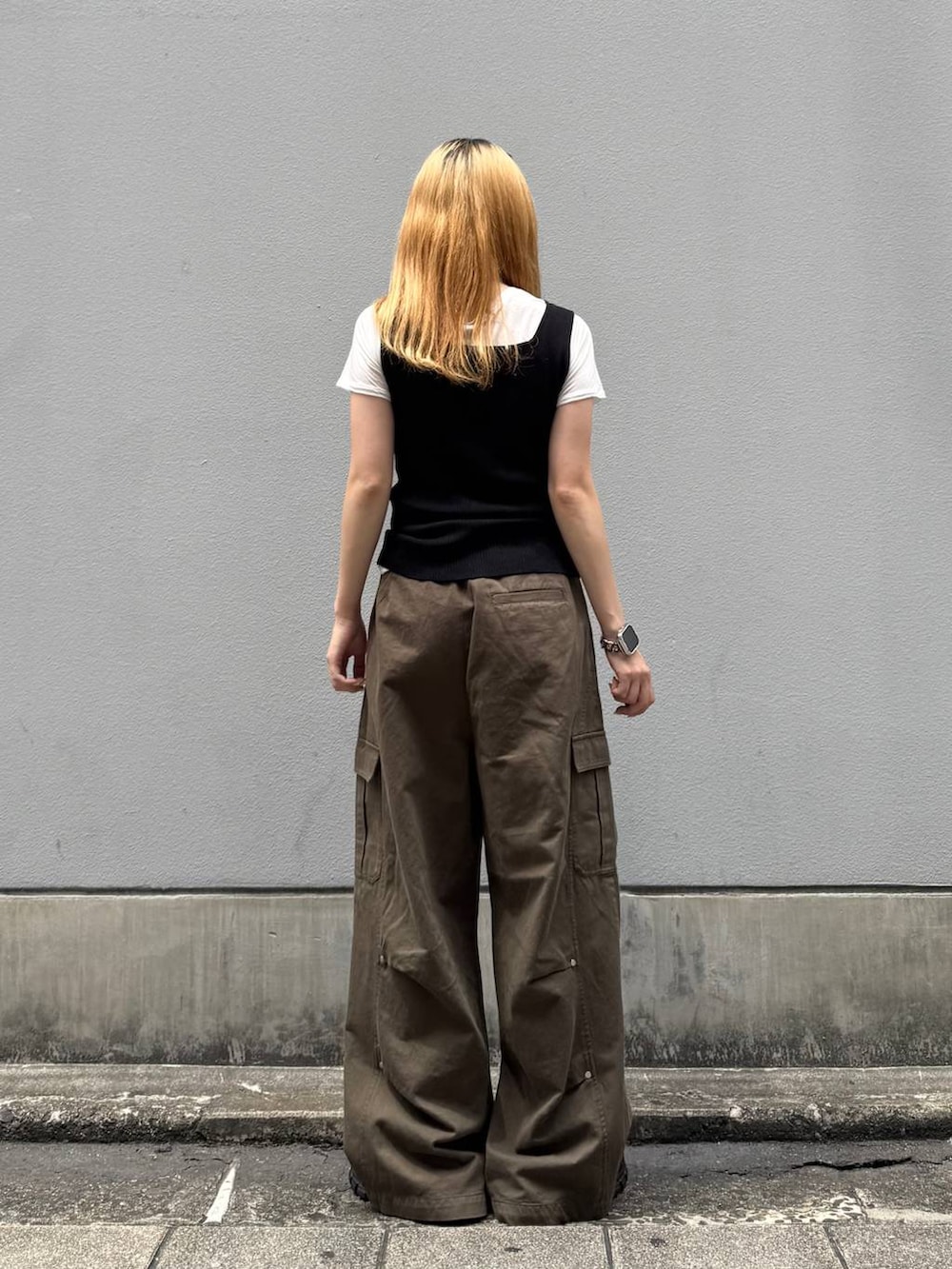 グリーン系のカーゴパンツ、ブラック系のタンクトップ、ブラック系のサンダルを着用したレディースの夏コーディネートの6枚目の写真