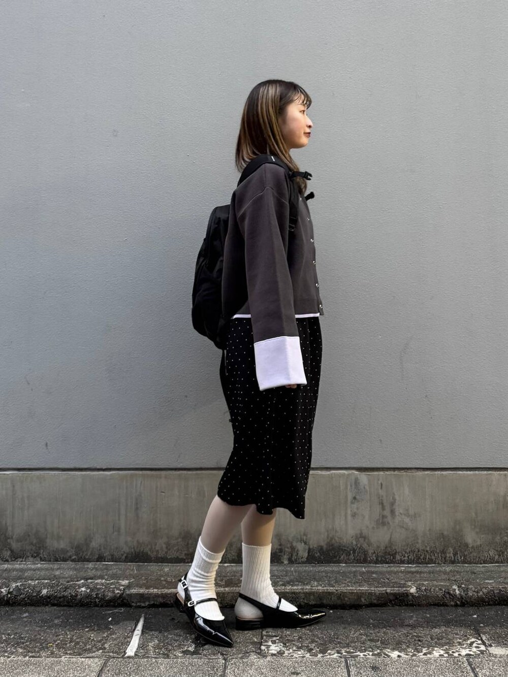 ブラック系のパンプス、グレー系のカーディガン/ボレロ、ブラック系のワンピースを着用したレディースの春コーディネートの7枚目の写真