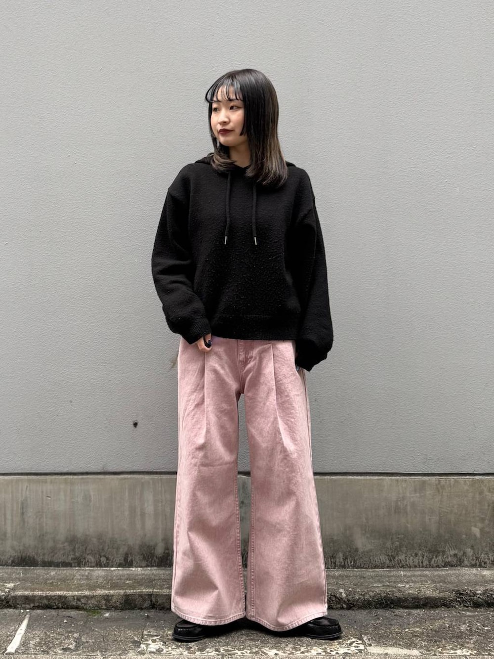 ピンク系のデニムパンツ、ブラック系のニット/セーターを着用したレディースの春コーディネートの4枚目の写真