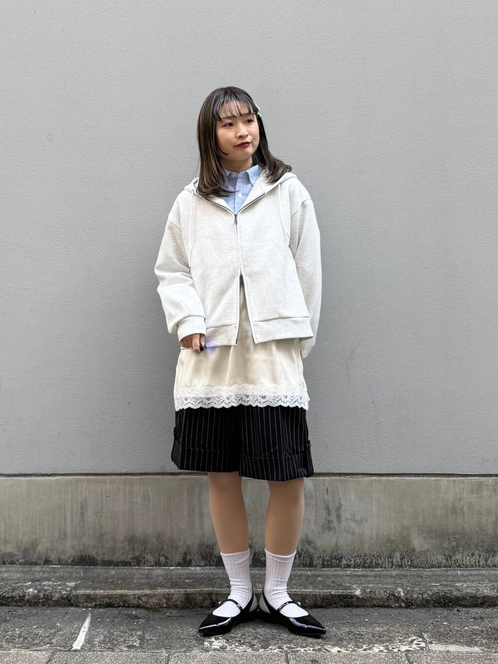 ブルー系のシャツ/ブラウス、ブラック系のパンプス、ホワイト系のパーカーを着用したレディースの春コーディネートの2枚目の写真
