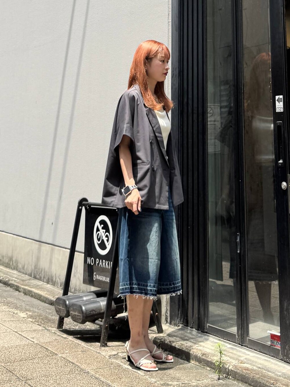 ブルー系のデニムパンツ、グレー系のテーラードジャケット、ホワイト系のキャミソールを着用したレディースの夏コーディネートの6枚目の写真