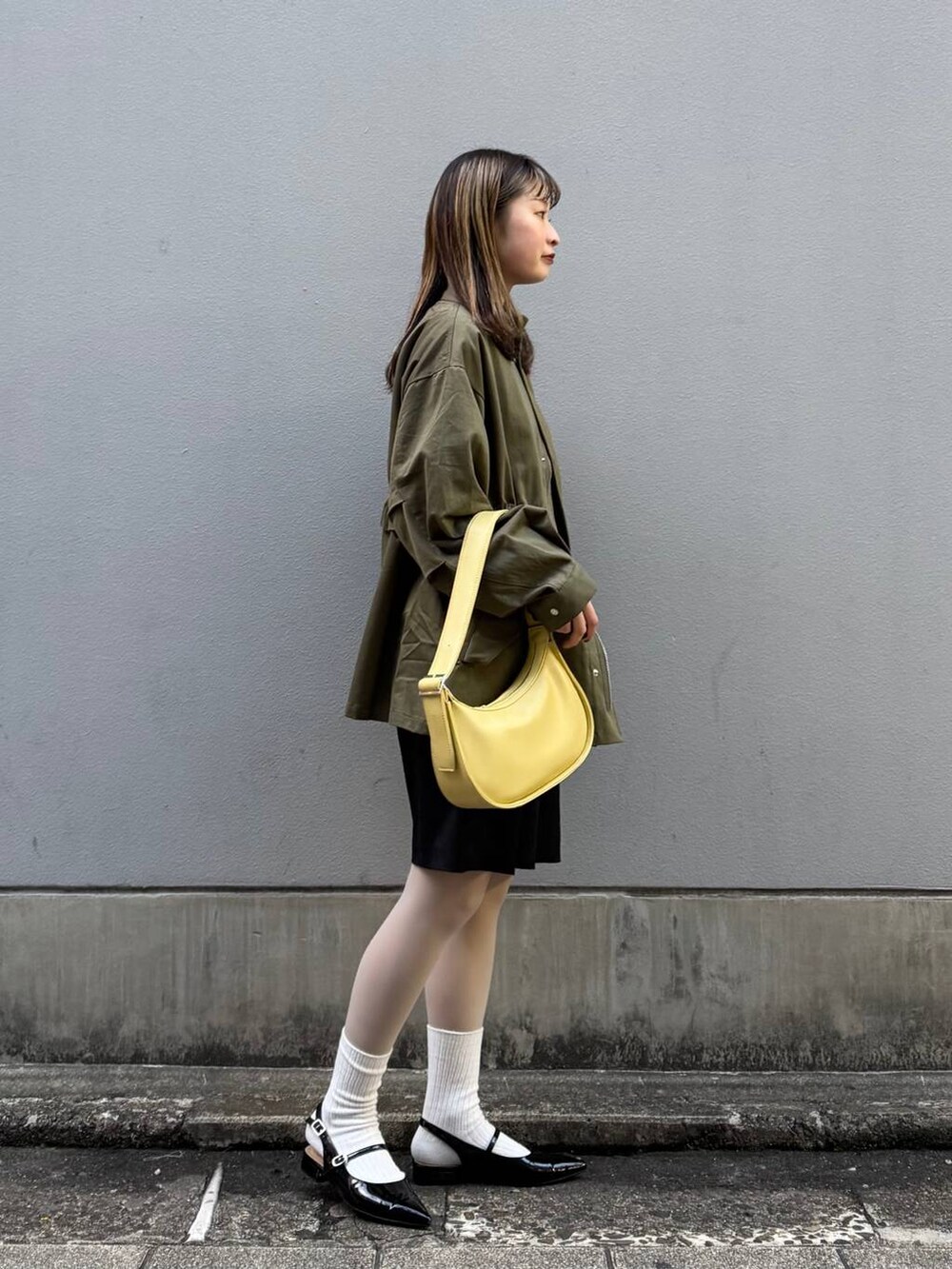 ブラック系のパンプス、ブラック系のスラックス、イエロー系のショルダーバッグを着用したレディースの春コーディネートの6枚目の写真