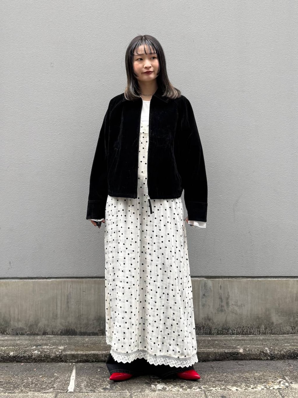 レッド系のパンプス、ブラック系のデニムパンツ、ブラック系のブルゾンを着用したレディースの春コーディネートの2枚目の写真