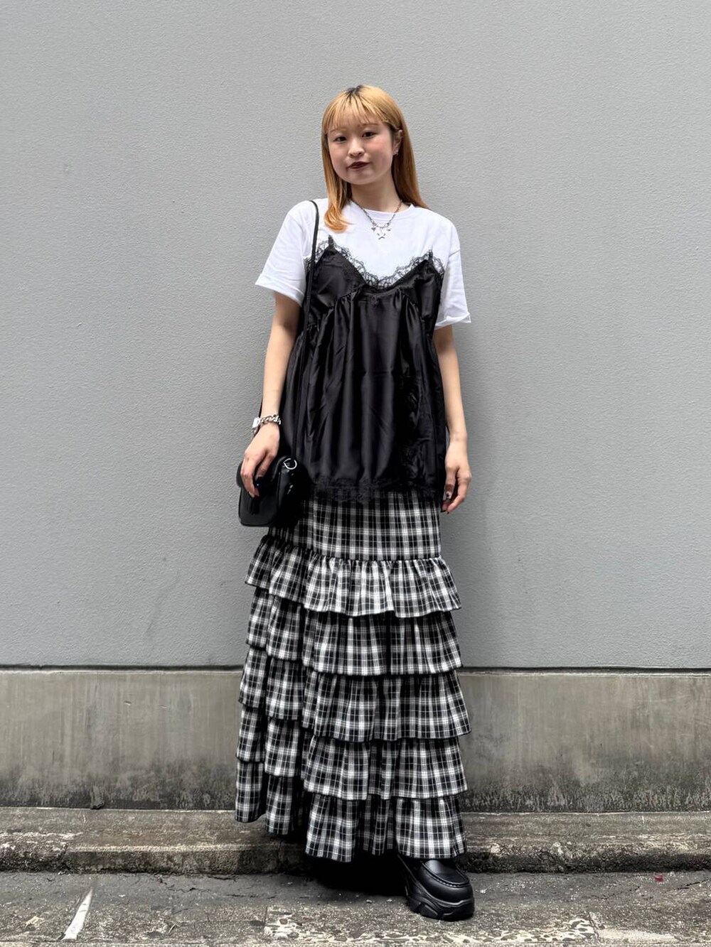ブラック系のローファー、ブラック系のスカート、ブラック系のショルダーバッグを着用したレディースの夏コーディネートの2枚目の写真