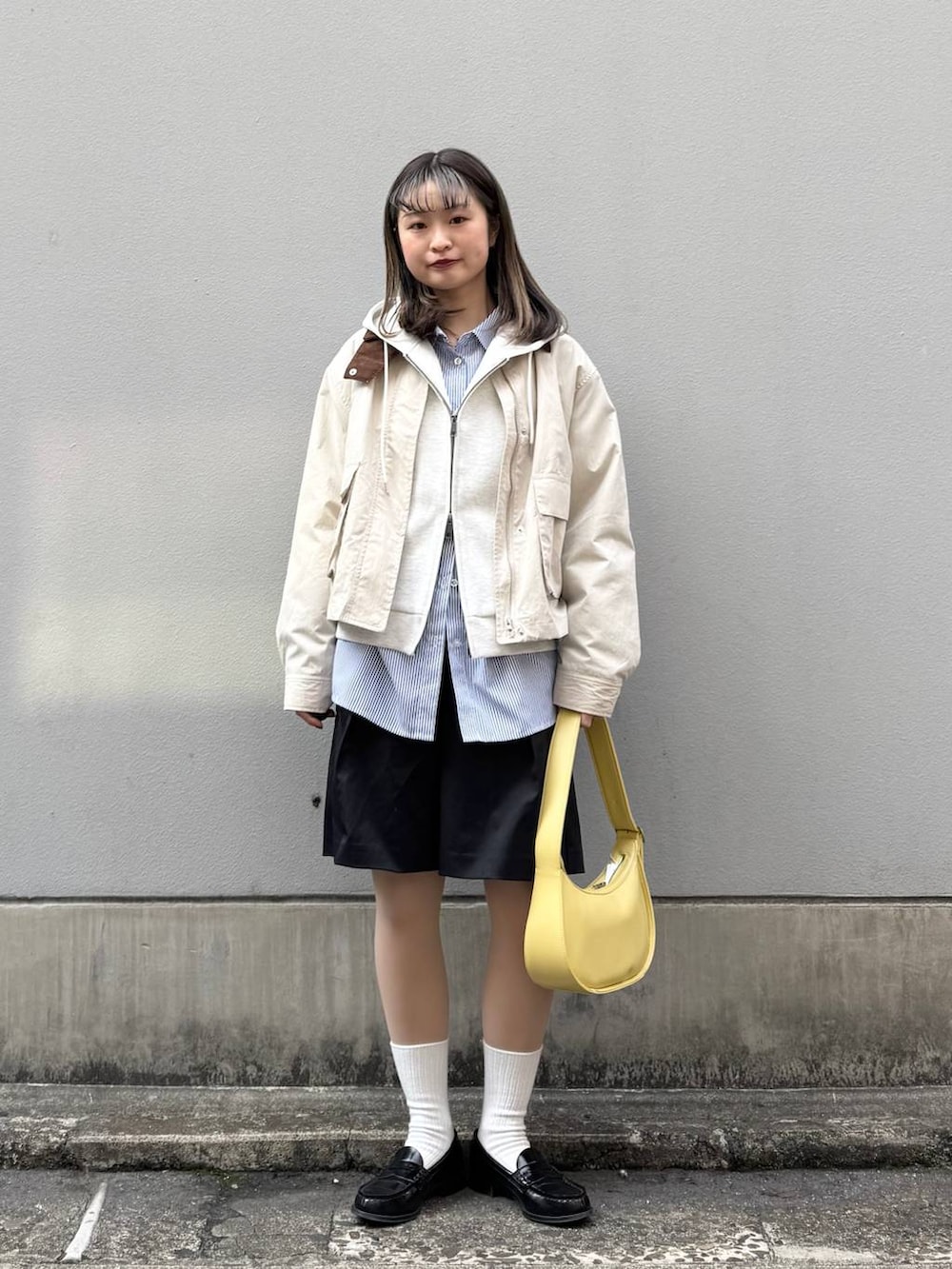 ホワイト系のパーカー、ブラック系のスラックス、イエロー系のショルダーバッグを着用したレディースの春コーディネートの3枚目の写真