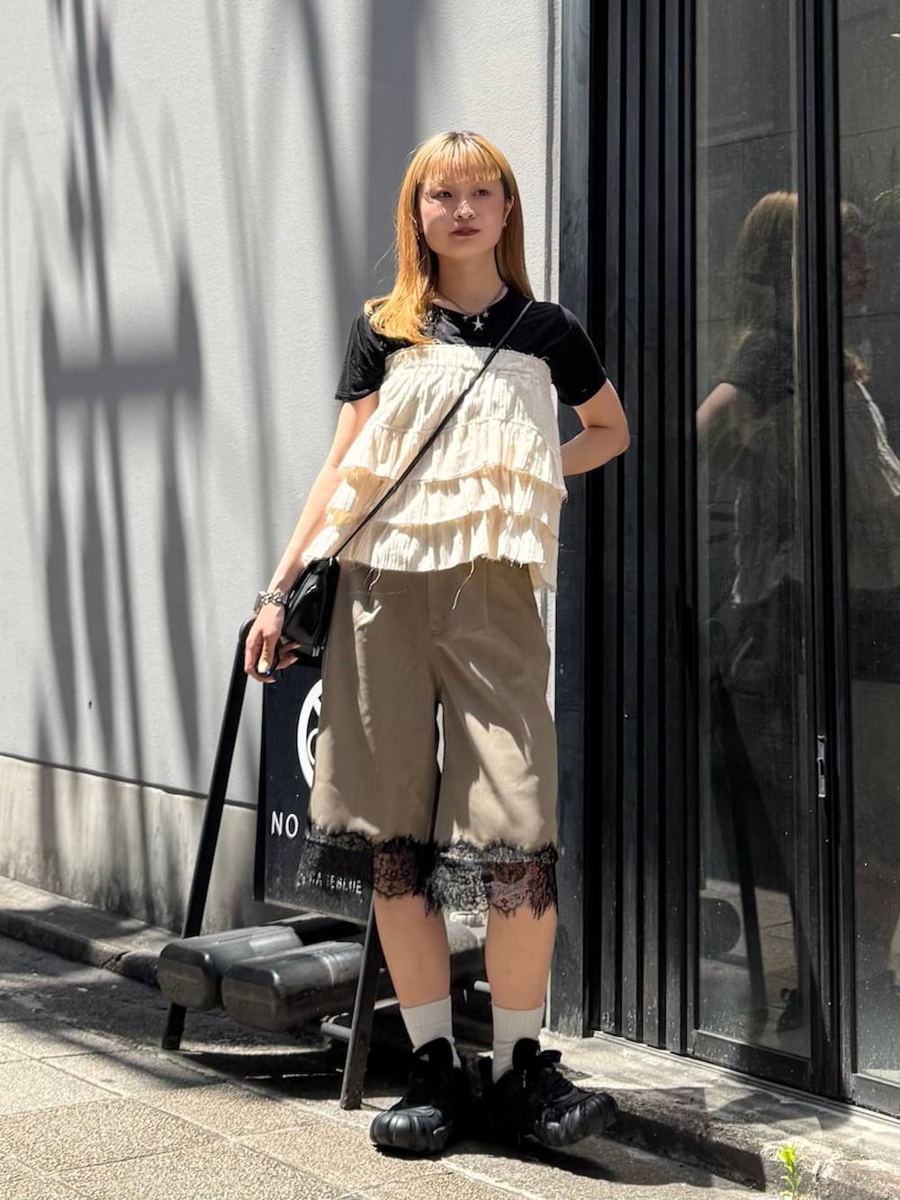 ブラック系のTシャツ/カットソー、ブラック系のショルダーバッグ、ブラウン系のスラックスを着用したレディースの夏コーディネートの2枚目の写真