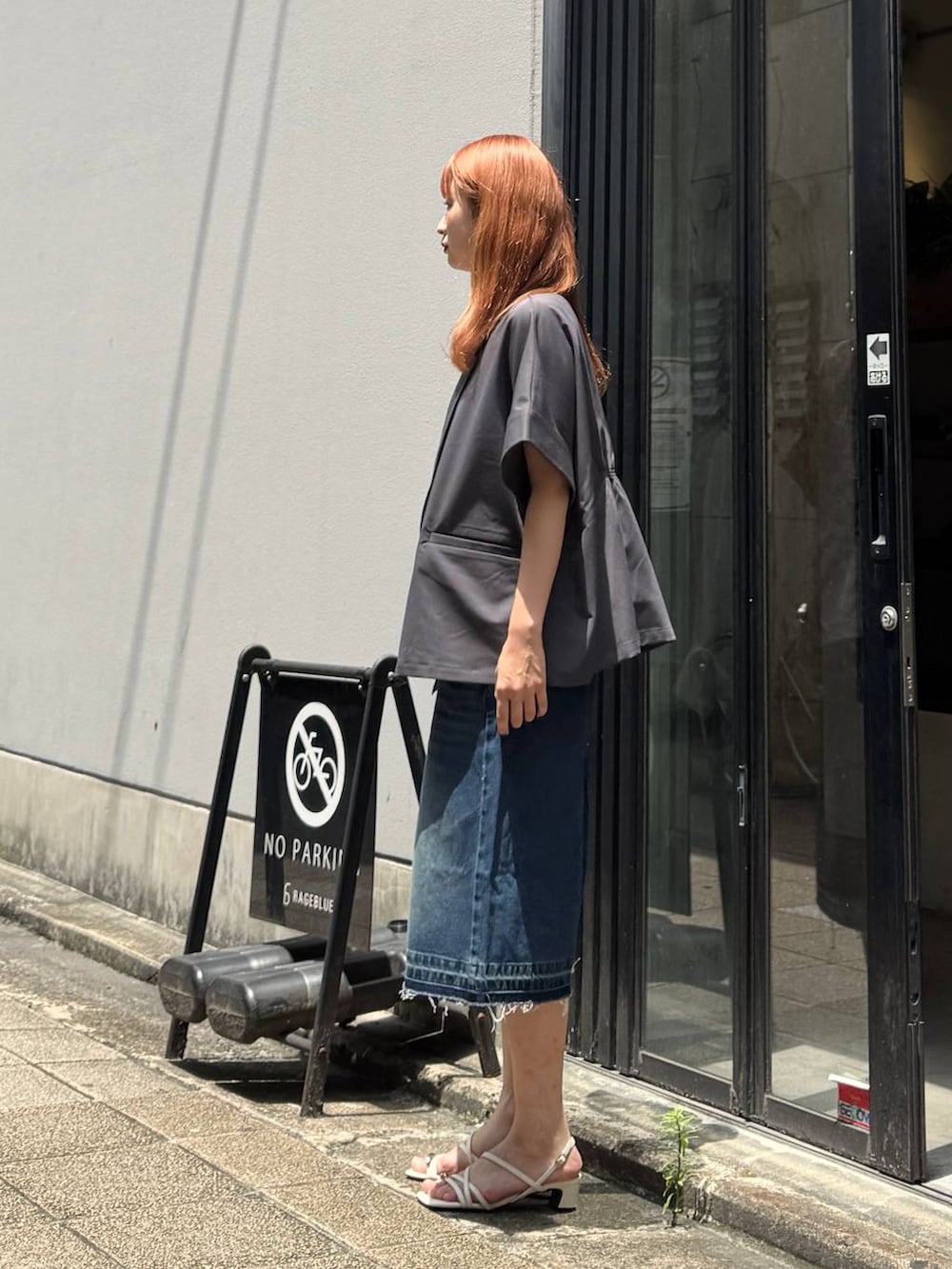 ブルー系のデニムパンツ、グレー系のテーラードジャケット、ホワイト系のキャミソールを着用したレディースの夏コーディネートの4枚目の写真