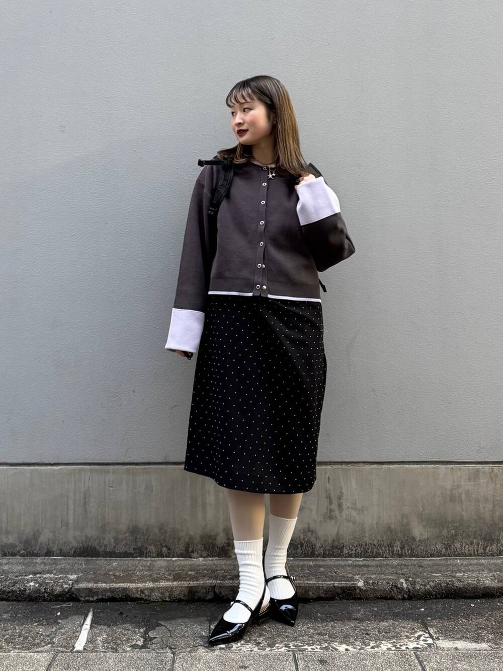 ブラック系のパンプス、グレー系のカーディガン/ボレロ、ブラック系のワンピースを着用したレディースの春コーディネートの2枚目の写真