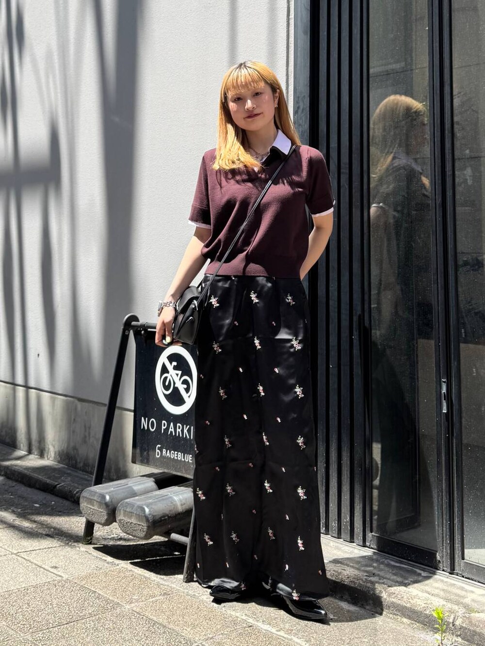 ブラック系のパンプス、ブラック系のスカート、ブラック系のショルダーバッグを着用したレディースの夏コーディネートの3枚目の写真