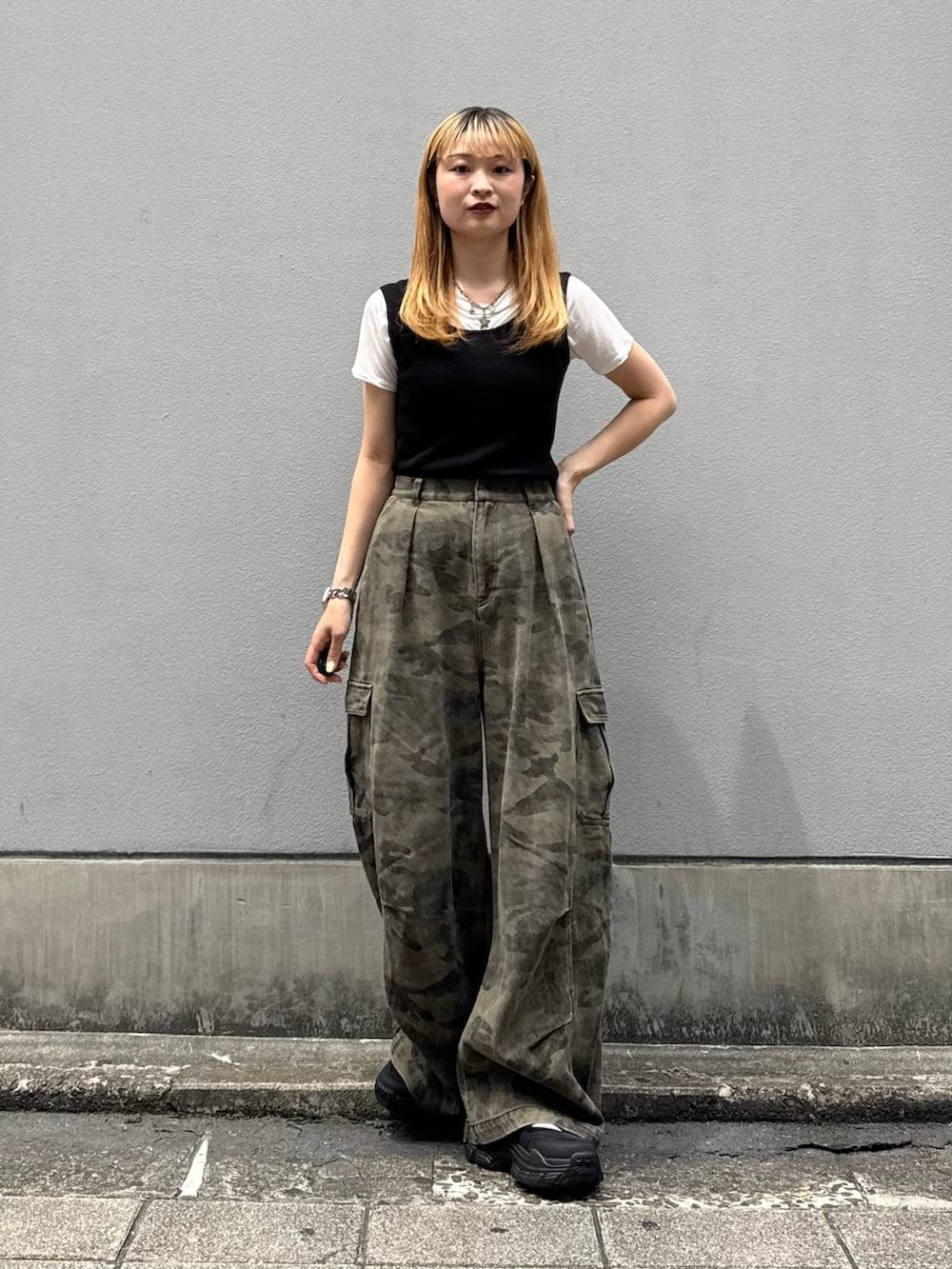 グリーン系のカーゴパンツ、ブラック系のタンクトップ、ブラック系のサンダルを着用したレディースの夏コーディネートの4枚目の写真