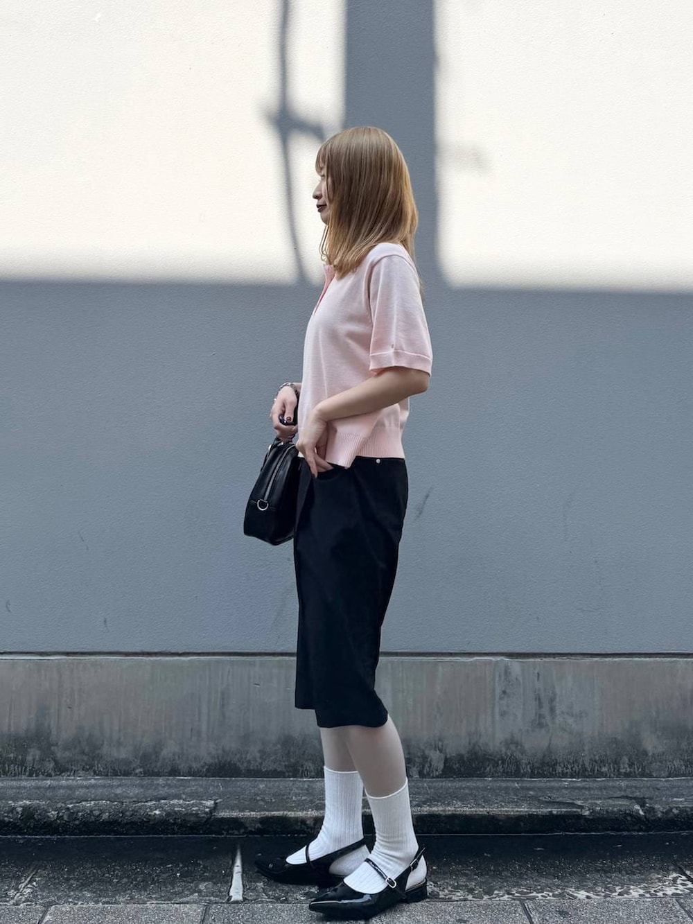 ブラック系のパンプス、ブラック系のスラックス、ブラック系のボストンバッグを着用したレディースの春コーディネートの5枚目の写真