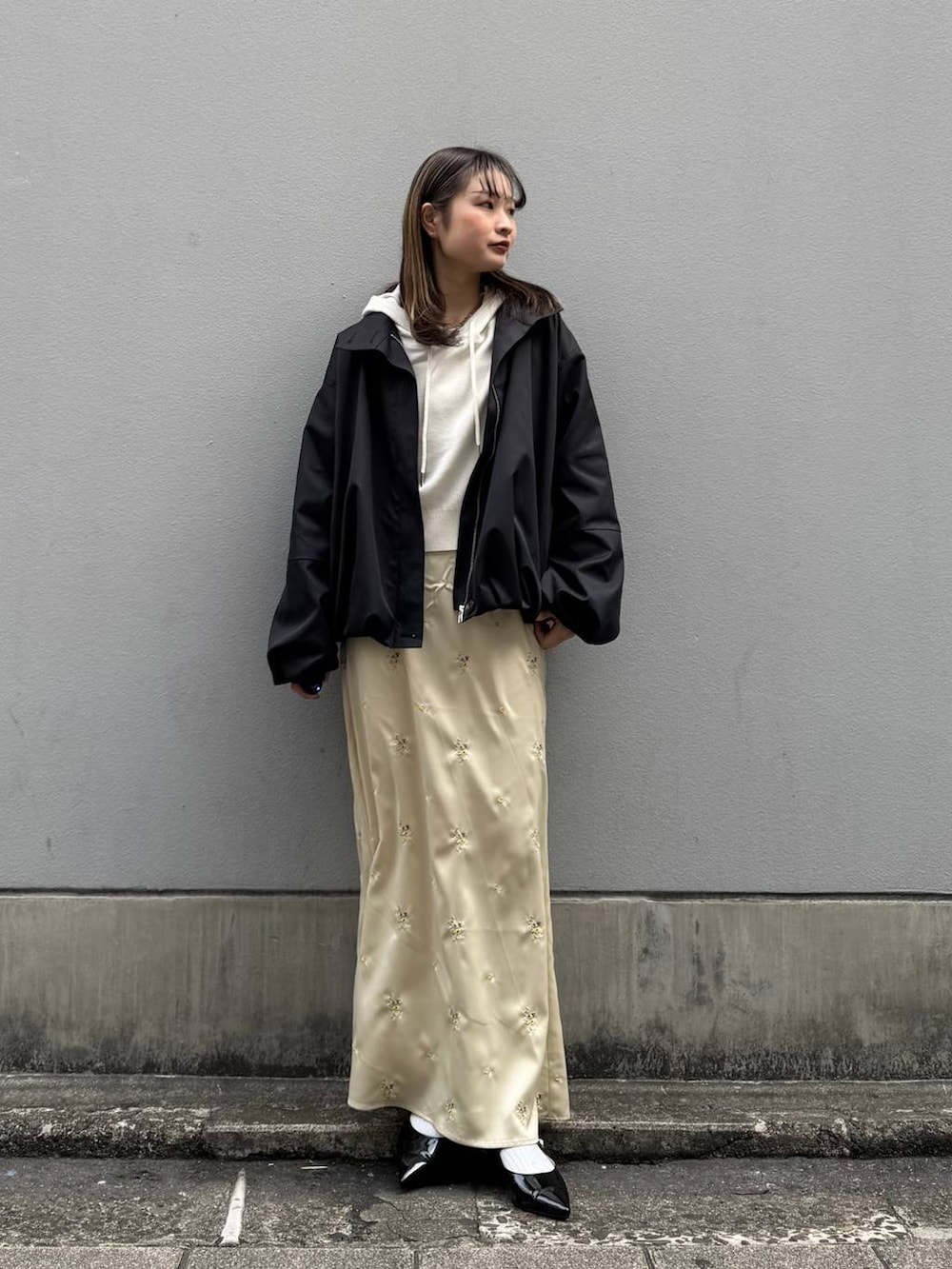 ブラック系のパンプス、ホワイト系のパーカー、ブラック系のブルゾンを着用したレディースの春コーディネートの2枚目の写真