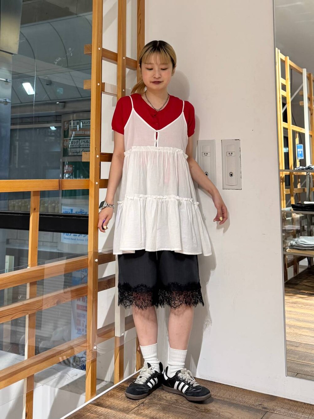ホワイト系のチュニック、ブラック系のスラックス、レッド系のカーディガン/ボレロを着用したレディースの夏コーディネートの2枚目の写真