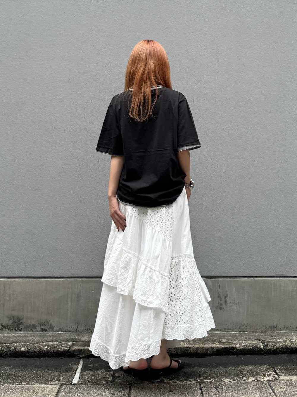 ホワイト系のスカート、ブラック系のTシャツ/カットソー、ブラック系のサンダルを着用したレディースの夏コーディネートの5枚目の写真