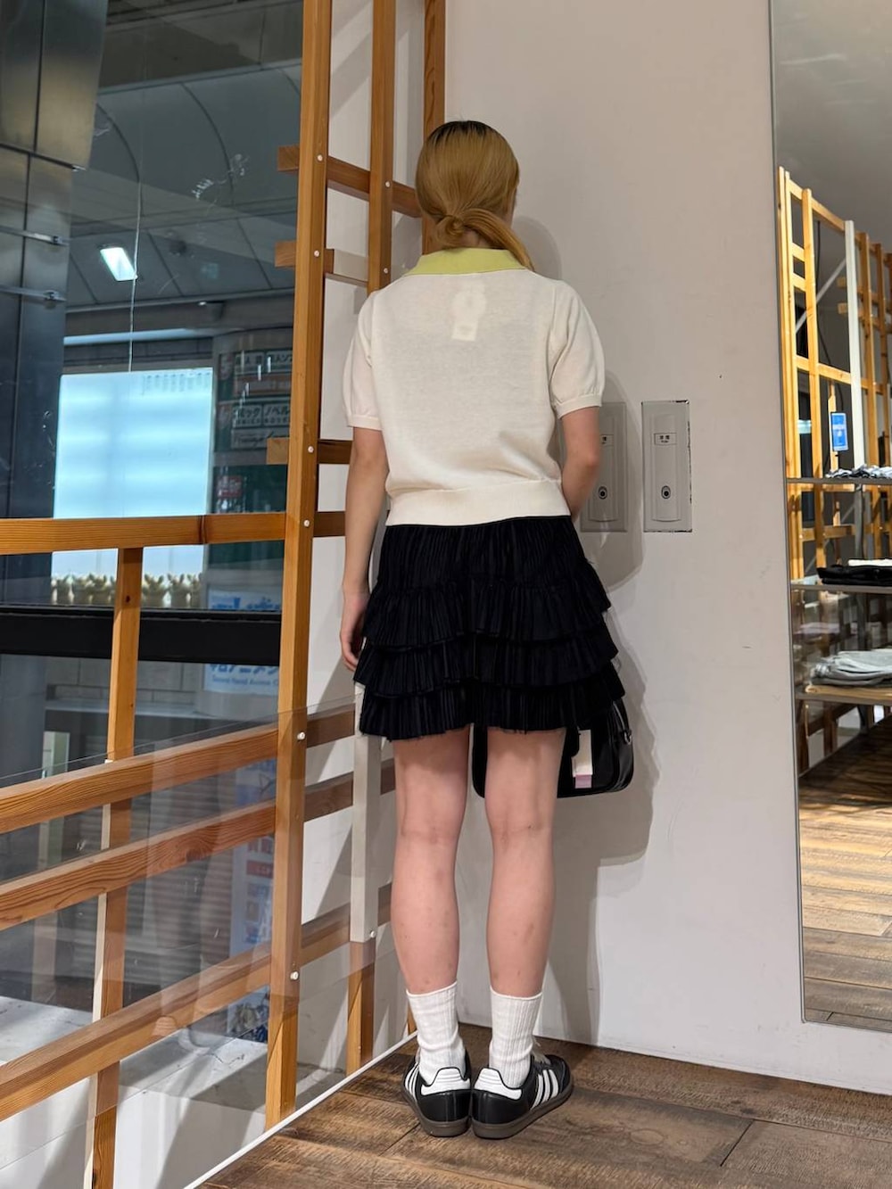 ブラック系のボストンバッグ、ブラック系のスカート、ホワイト系のポロシャツを着用したレディースの夏コーディネートの5枚目の写真