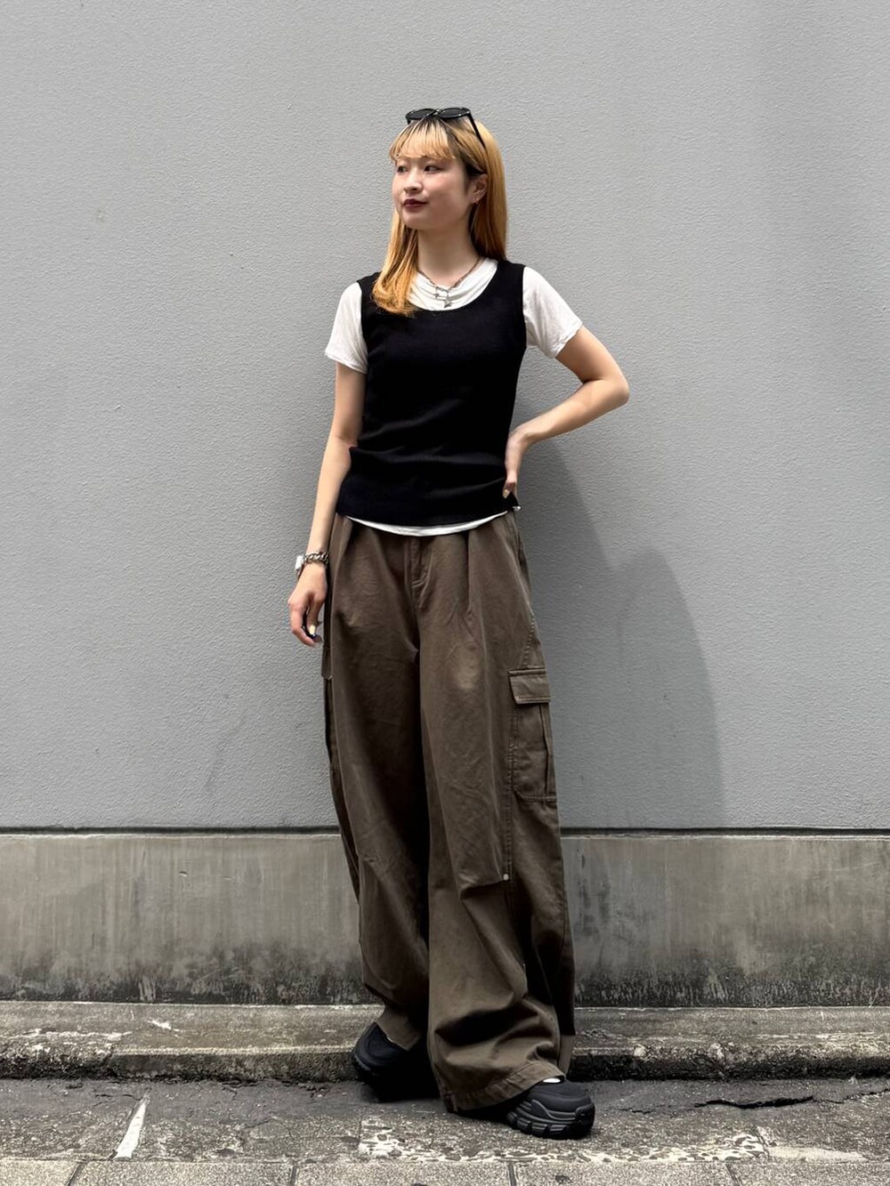 グリーン系のカーゴパンツ、ブラック系のタンクトップ、ブラック系のサンダルを着用したレディースの夏コーディネートの3枚目の写真