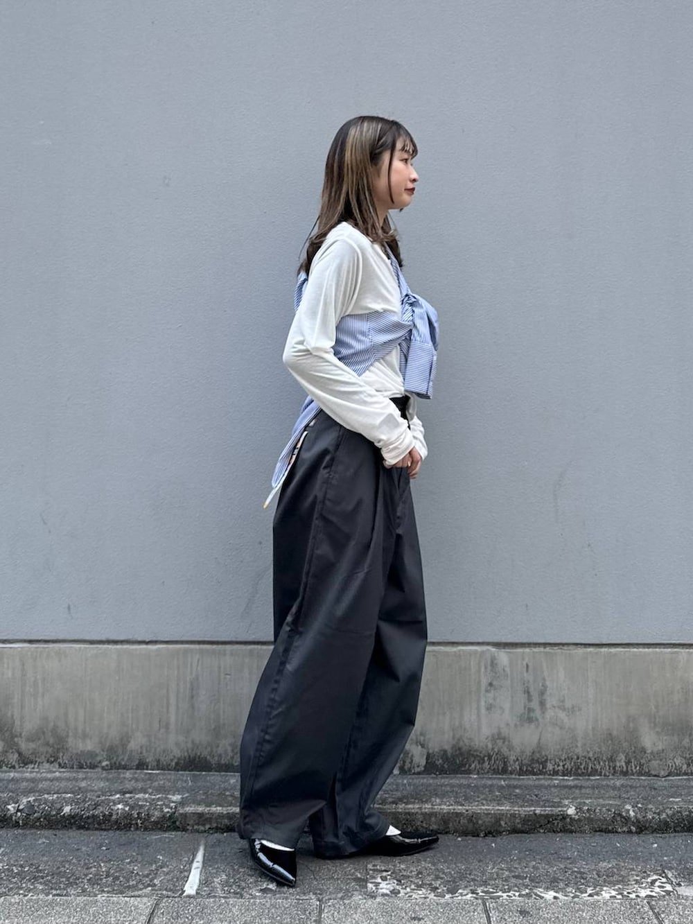 グレー系のチノパンツ、ブラック系のパンプス、ブルー系のシャツ/ブラウスを着用したレディースの春コーディネートの7枚目の写真