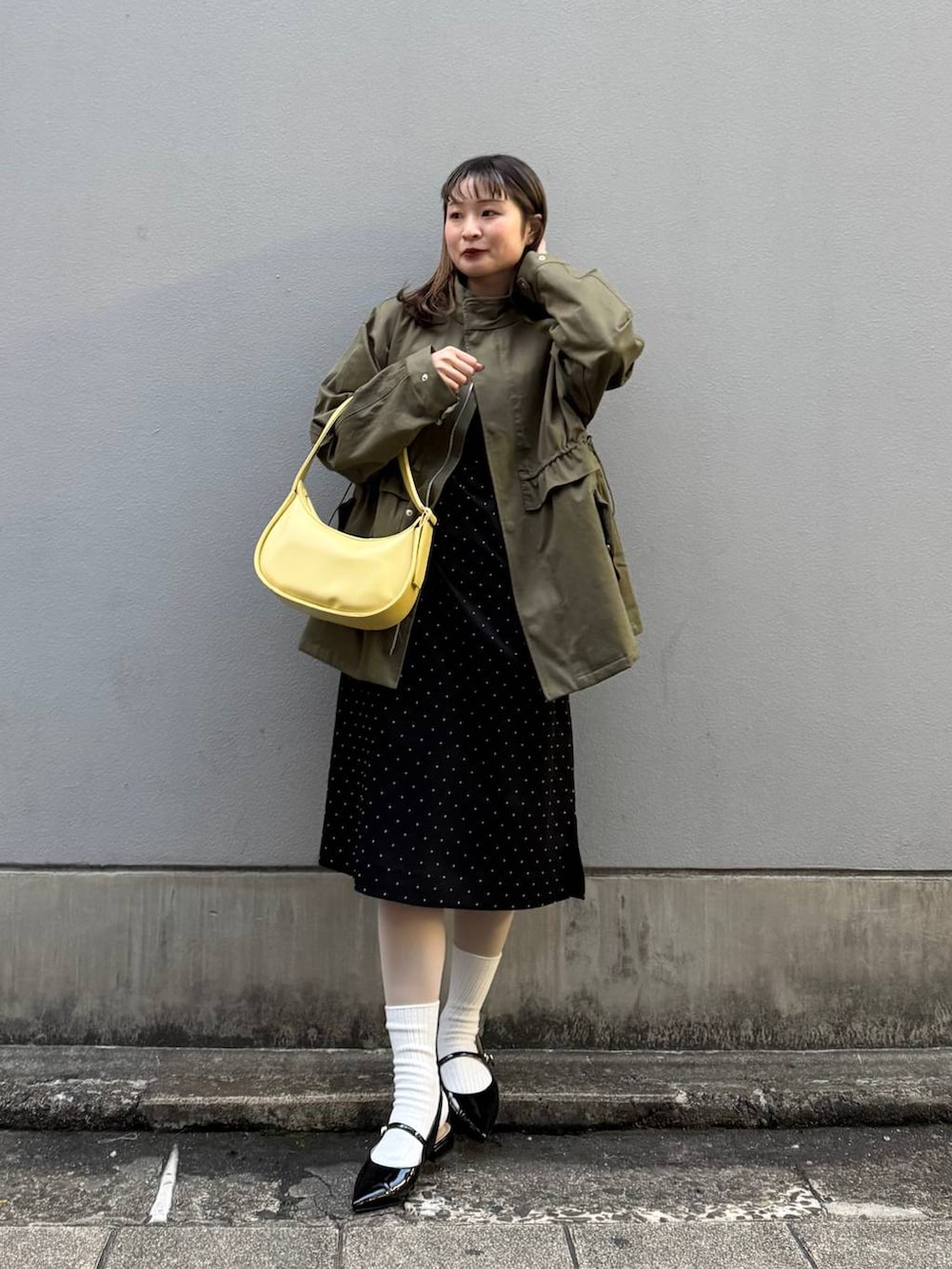 ブラック系のパンプス、イエロー系のショルダーバッグ、ブラック系のワンピースを着用したレディースの春コーディネートの2枚目の写真