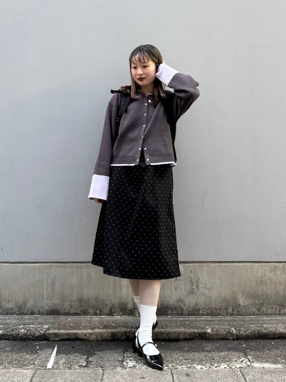 ブラック系のパンプス、グレー系のカーディガン/ボレロ、ブラック系のワンピースを着用したレディースの春コーディネートの4枚目の写真