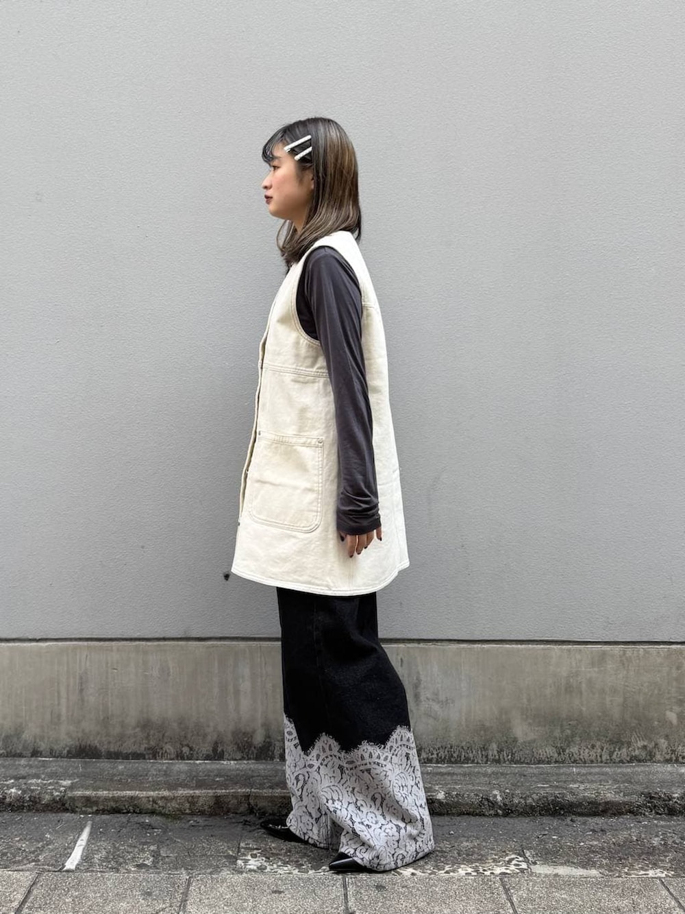 ブラック系のパンプス、ホワイト系のワンピース、ブラック系のデニムパンツを着用したレディースの春コーディネートの4枚目の写真