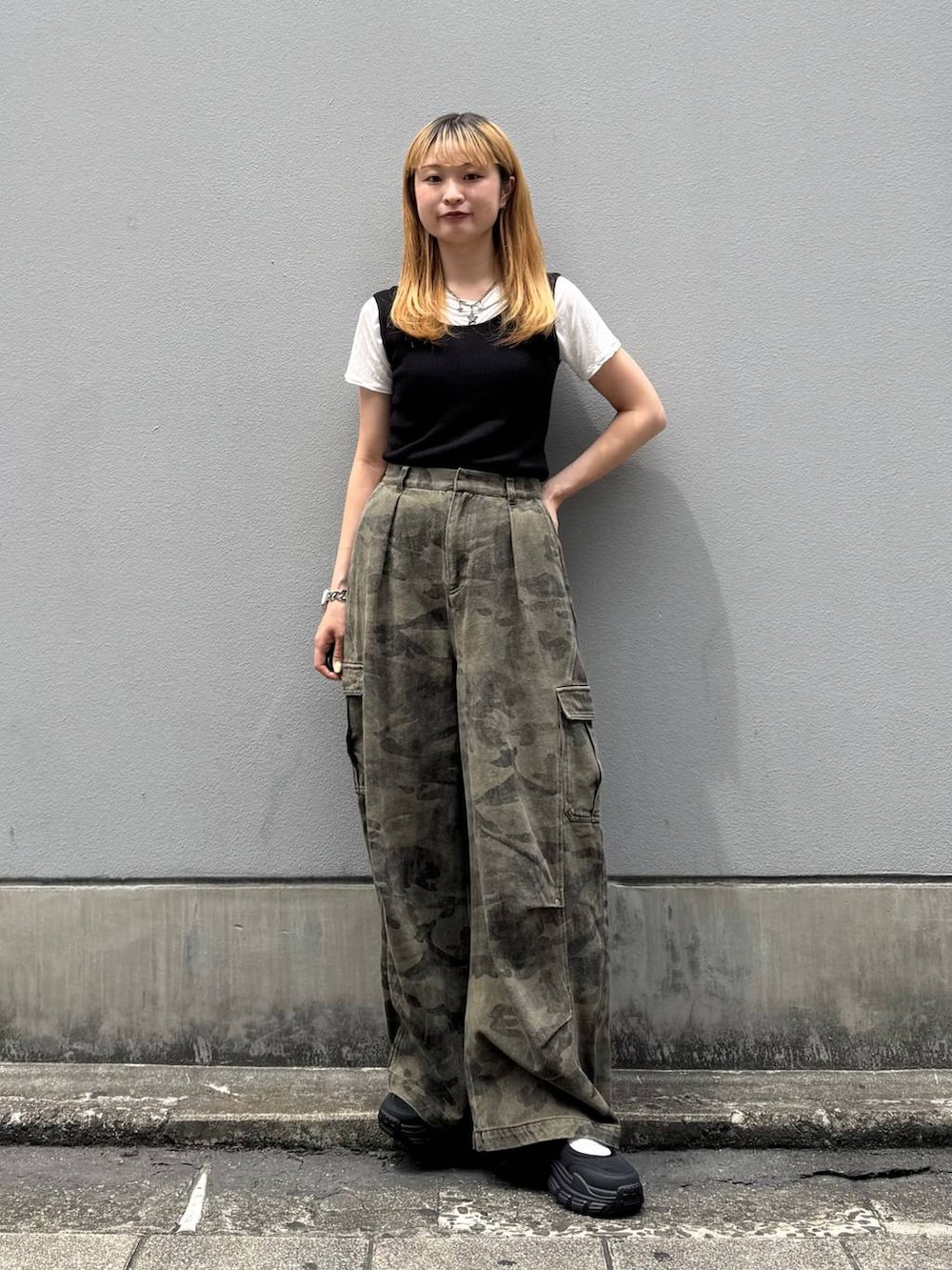 グリーン系のカーゴパンツ、ブラック系のタンクトップ、ブラック系のサンダルを着用したレディースの夏コーディネートの2枚目の写真