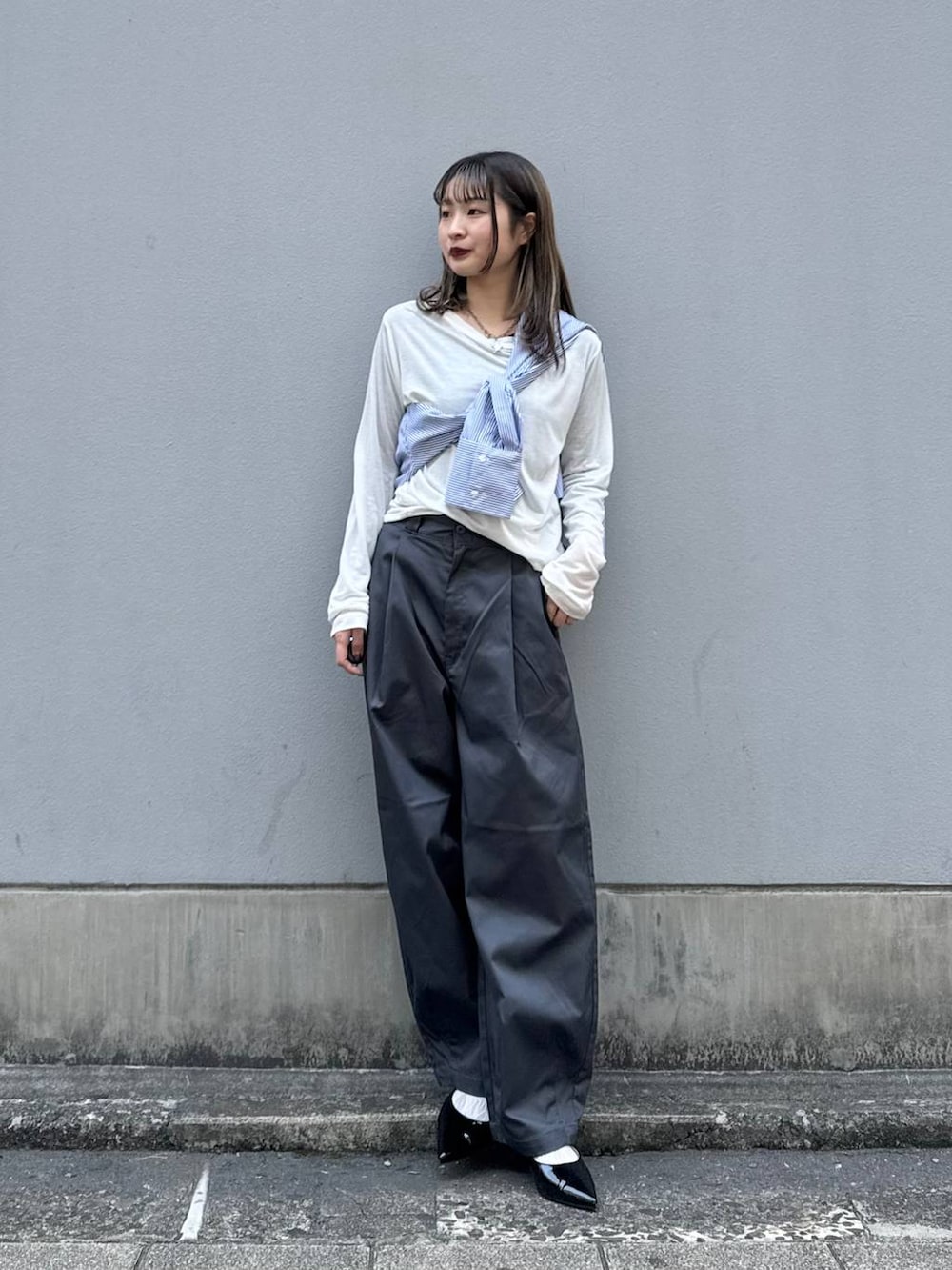グレー系のチノパンツ、ブラック系のパンプス、ブルー系のシャツ/ブラウスを着用したレディースの春コーディネートの2枚目の写真