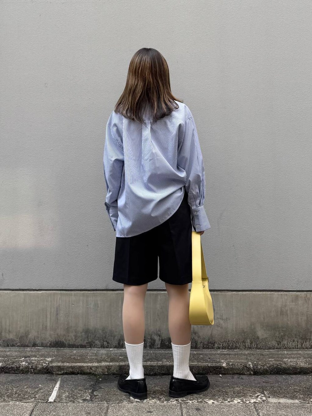 ブラック系のスラックス、イエロー系のショルダーバッグ、ブルー系のシャツ/ブラウスを着用したレディースの春コーディネートの5枚目の写真