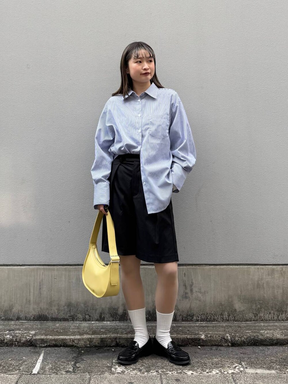 ブラック系のスラックス、イエロー系のショルダーバッグ、ブルー系のシャツ/ブラウスを着用したレディースの春コーディネートの3枚目の写真