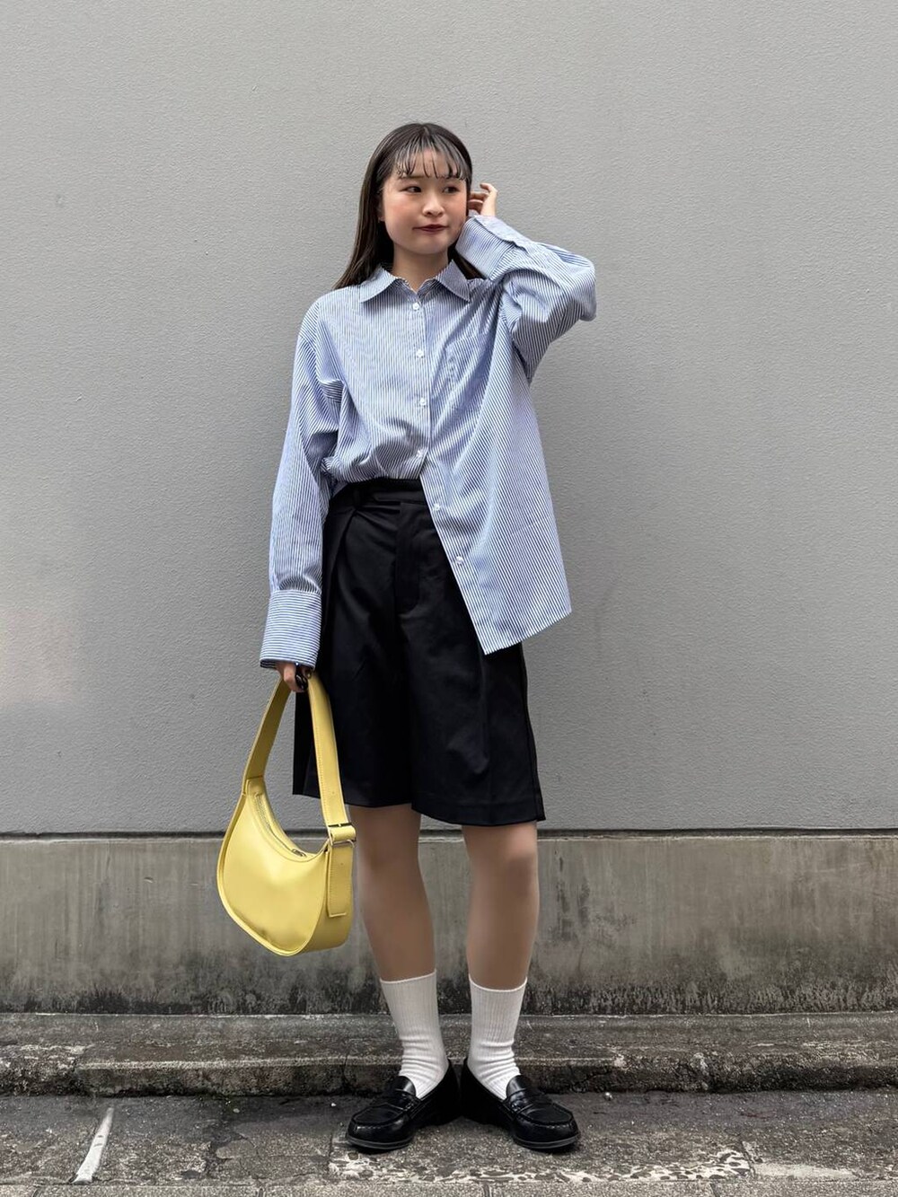 ブラック系のスラックス、イエロー系のショルダーバッグ、ブルー系のシャツ/ブラウスを着用したレディースの春コーディネートの2枚目の写真