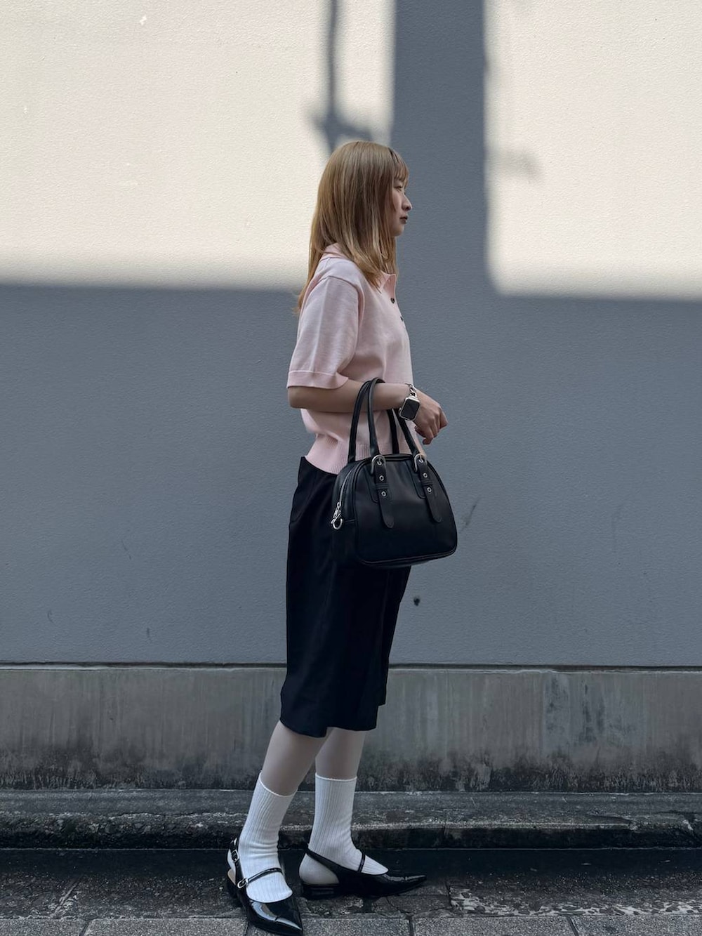 ブラック系のパンプス、ブラック系のスラックス、ブラック系のボストンバッグを着用したレディースの春コーディネートの7枚目の写真