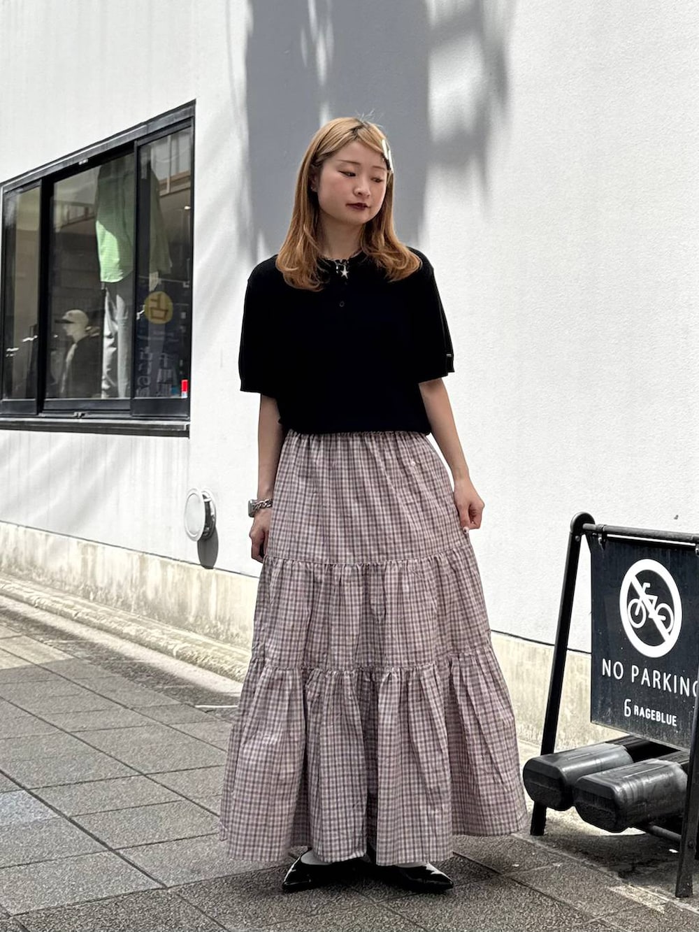 ブラック系のパンプス、ブラック系のポロシャツ、ベージュ系のスカートを着用したレディースの春コーディネートの2枚目の写真