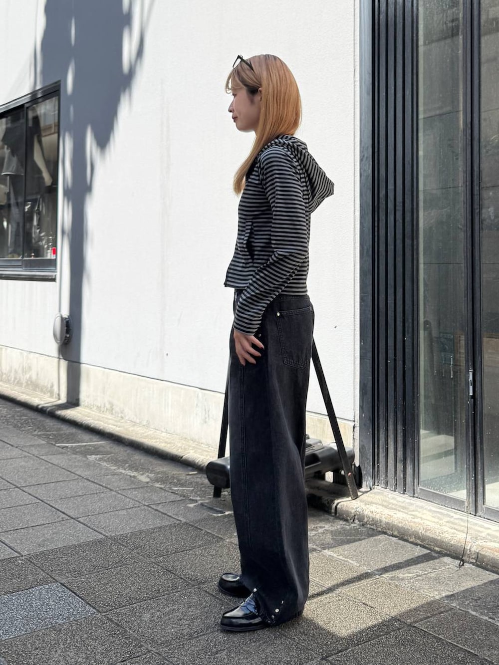 ブラック系のパーカー、グレー系のデニムパンツを着用したレディースの夏コーディネートの5枚目の写真