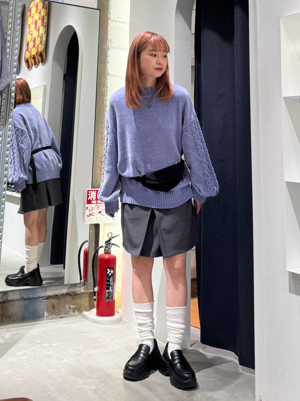 ブルー系のニット/セーター、グレー系のスカート、ブラック系のボディバッグ/ウエストポーチを着用したレディースの秋コーディネートの4枚目の写真