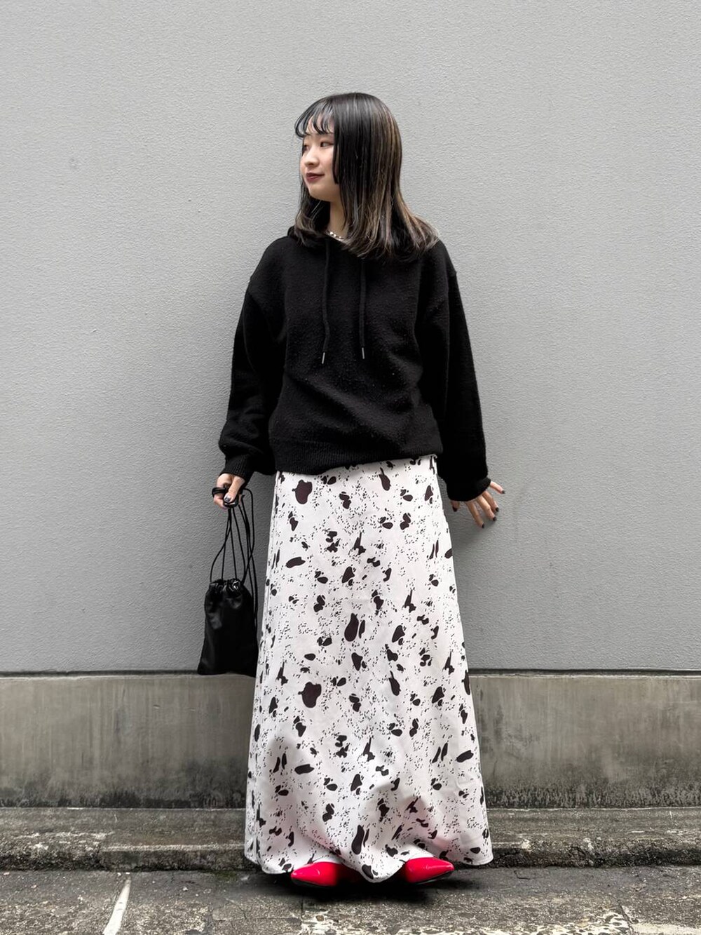 ブラック系のショルダーバッグ、レッド系のパンプス、ブラウン系のスカートを着用したレディースの春コーディネートの4枚目の写真