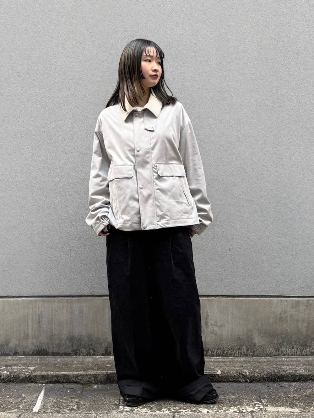 グレー系のブルゾン、ブラック系のチノパンツを着用したレディースの春コーディネートの3枚目の写真