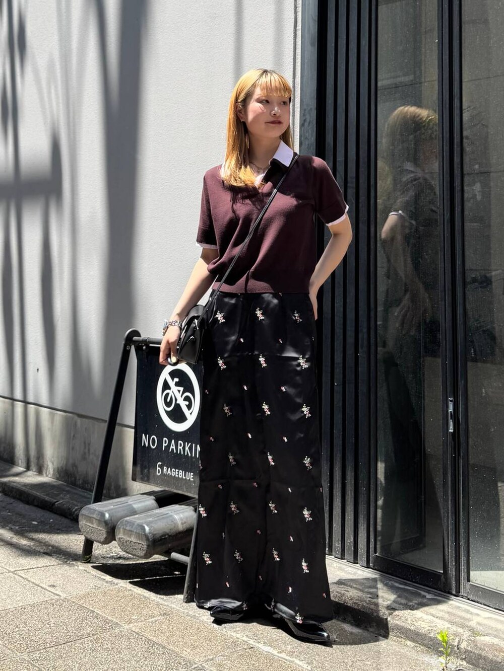 ブラック系のパンプス、ブラック系のスカート、ブラック系のショルダーバッグを着用したレディースの夏コーディネートの2枚目の写真