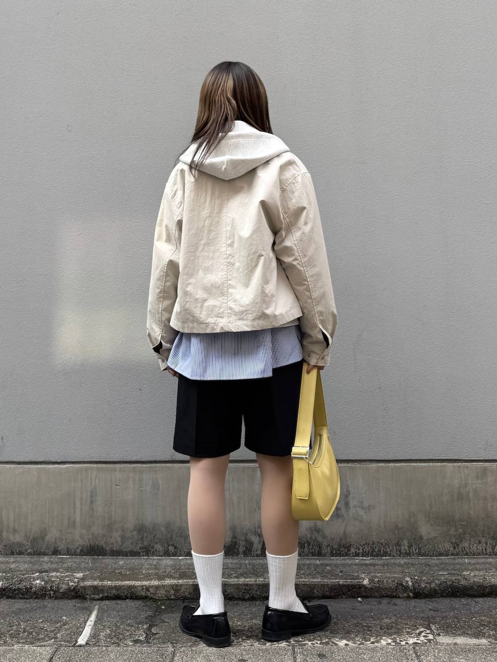 ホワイト系のパーカー、ブラック系のスラックス、イエロー系のショルダーバッグを着用したレディースの春コーディネートの5枚目の写真