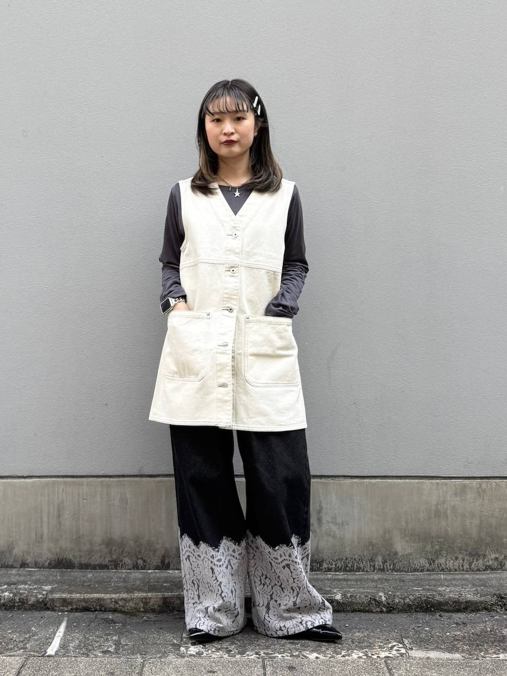 ブラック系のパンプス、ホワイト系のワンピース、ブラック系のデニムパンツを着用したレディースの春コーディネートの3枚目の写真