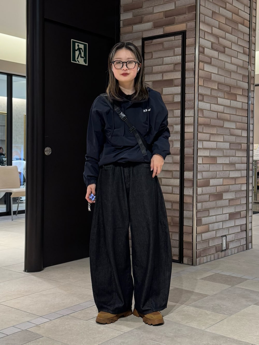 ブルー系のナイロンジャケット、ブラック系のデニムパンツ、ブラウン系のスニーカーを着用したレディースの春コーディネートの3枚目の写真