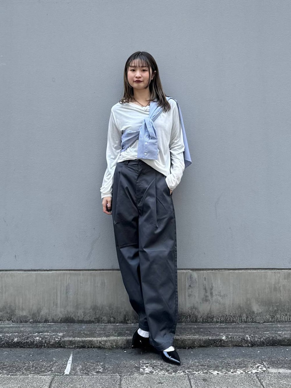 グレー系のチノパンツ、ブラック系のパンプス、ブルー系のシャツ/ブラウスを着用したレディースの春コーディネートの3枚目の写真