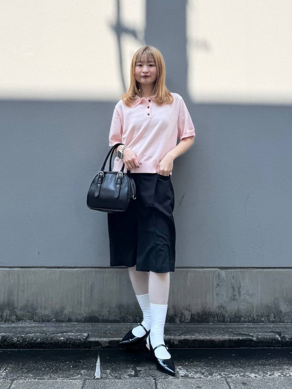 ブラック系のパンプス、ブラック系のスラックス、ブラック系のボストンバッグを着用したレディースの春コーディネートの2枚目の写真