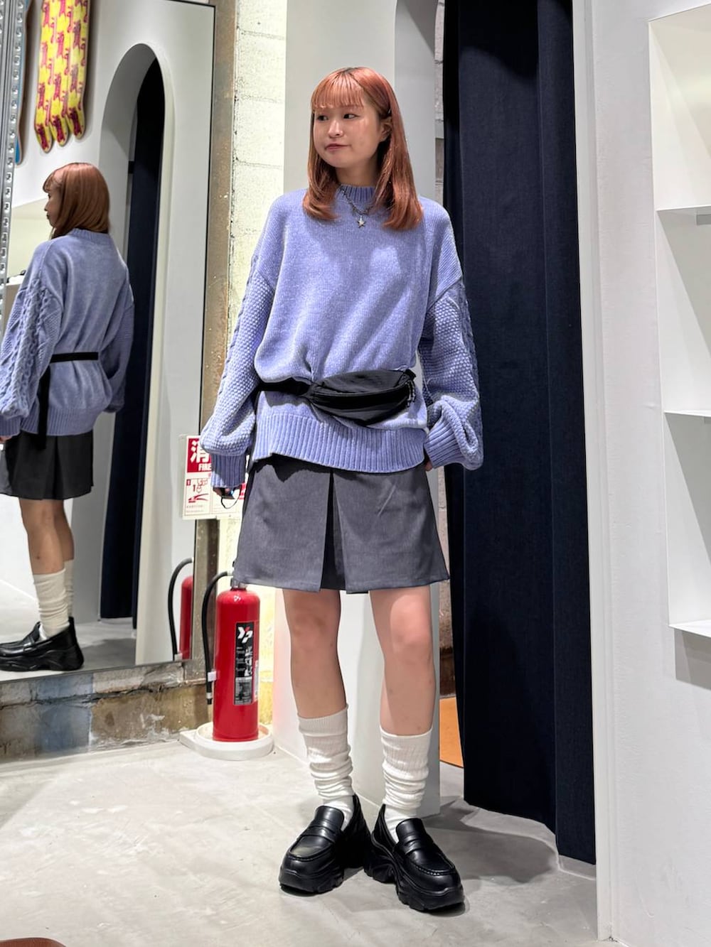 ブルー系のニット/セーター、グレー系のスカート、ブラック系のボディバッグ/ウエストポーチを着用したレディースの秋コーディネートの2枚目の写真