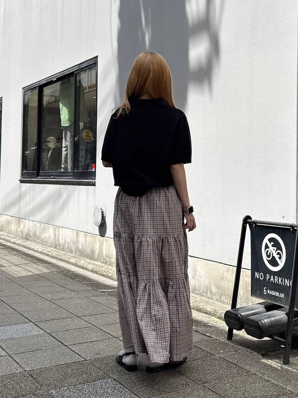 ブラック系のパンプス、ブラック系のポロシャツ、ベージュ系のスカートを着用したレディースの春コーディネートの6枚目の写真