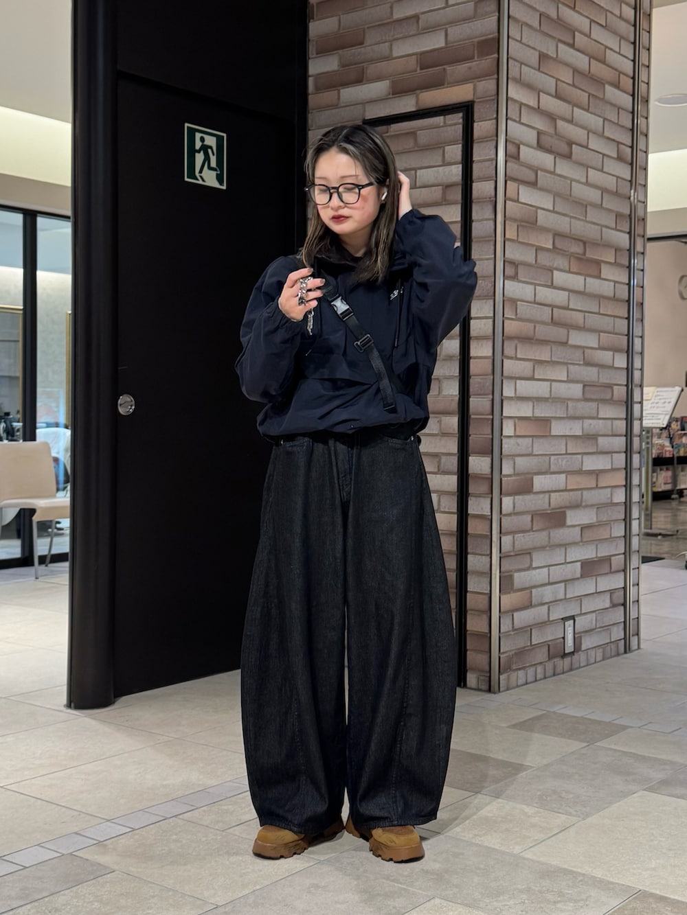 ブルー系のナイロンジャケット、ブラック系のデニムパンツ、ブラウン系のスニーカーを着用したレディースの春コーディネートの2枚目の写真