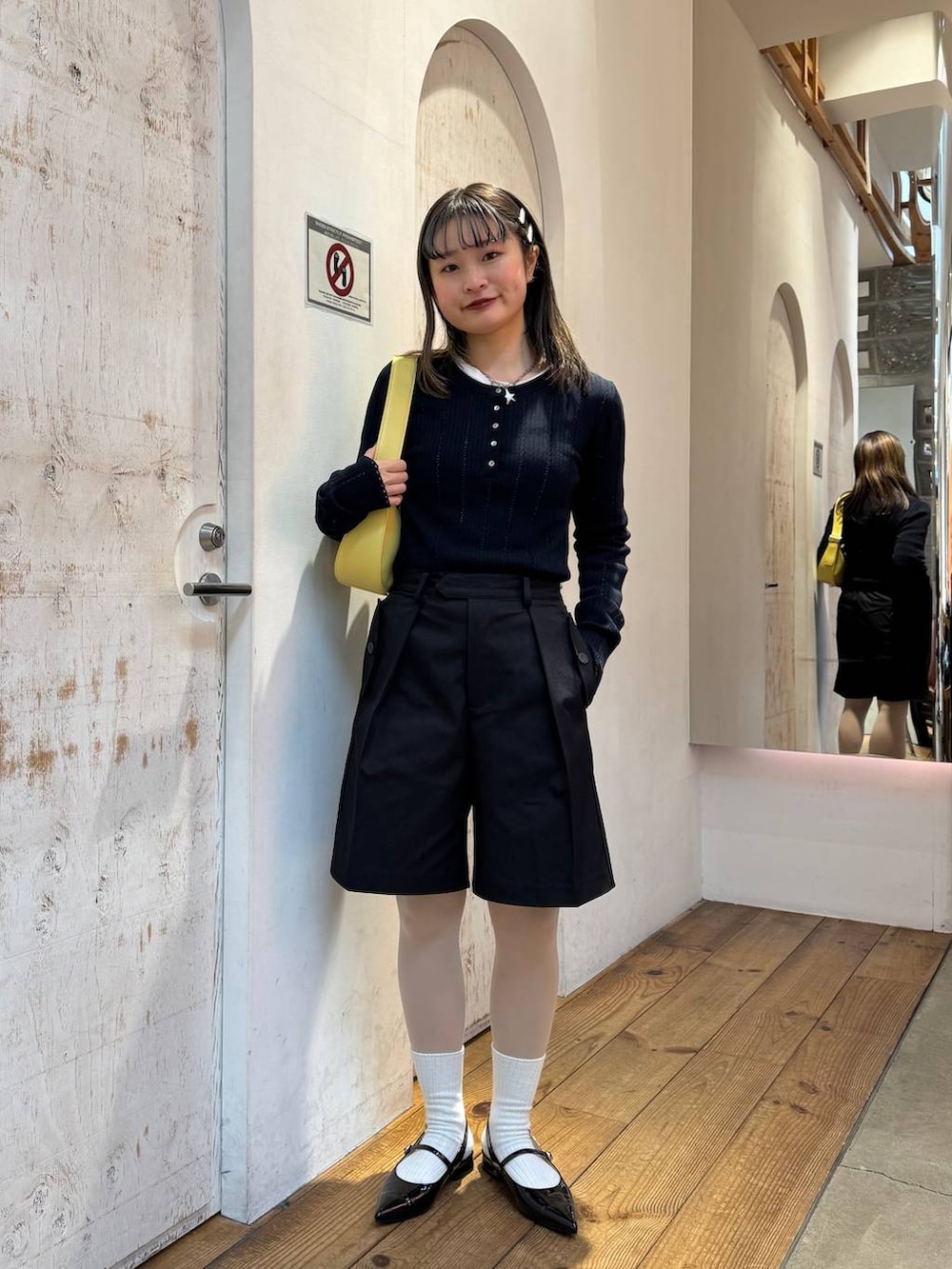 ブラック系のパンプス、ブラック系のスラックス、イエロー系のショルダーバッグを着用したレディースの春コーディネートの2枚目の写真