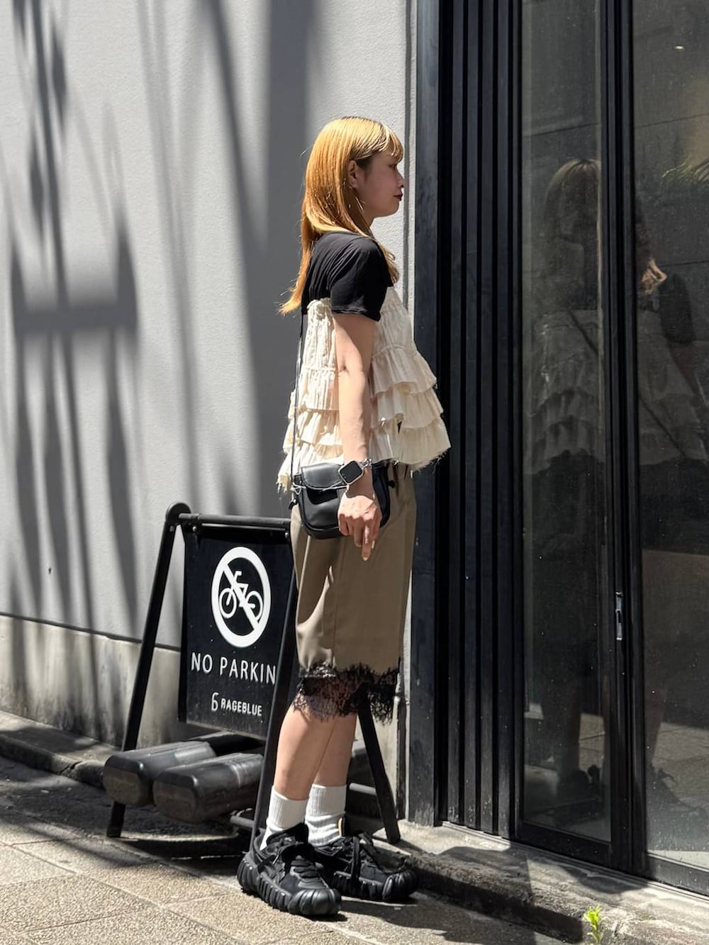 ブラック系のTシャツ/カットソー、ブラック系のショルダーバッグ、ブラウン系のスラックスを着用したレディースの夏コーディネートの6枚目の写真