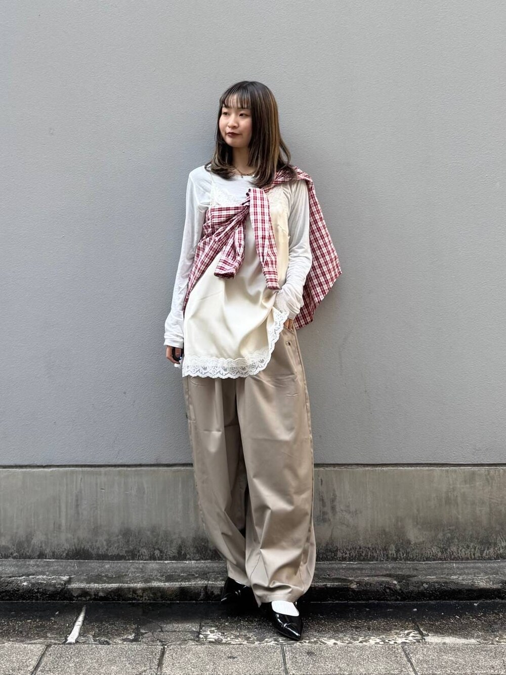 ブラック系のパンプス、ホワイト系のキャミソール、ベージュ系のスラックスを着用したレディースの春コーディネートの3枚目の写真